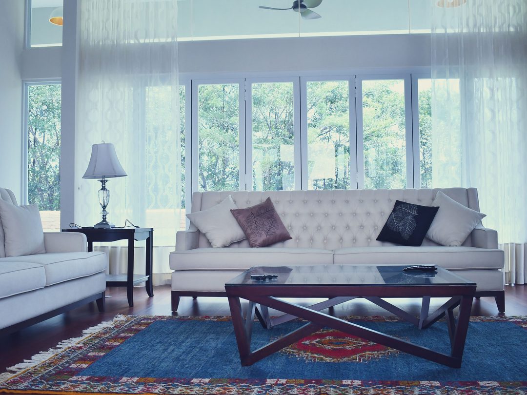 Living room with tufted white sofas and a blue patterned rug