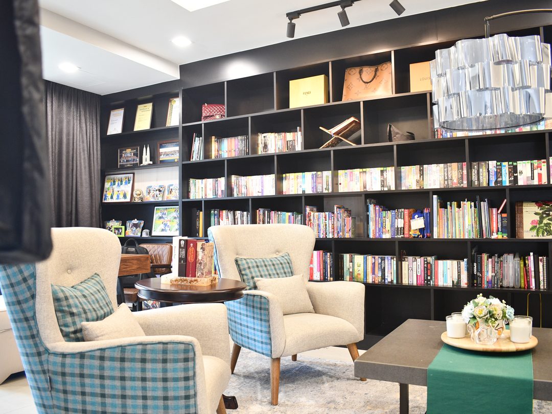 Reading lounge with a full-height library wall and armchairs