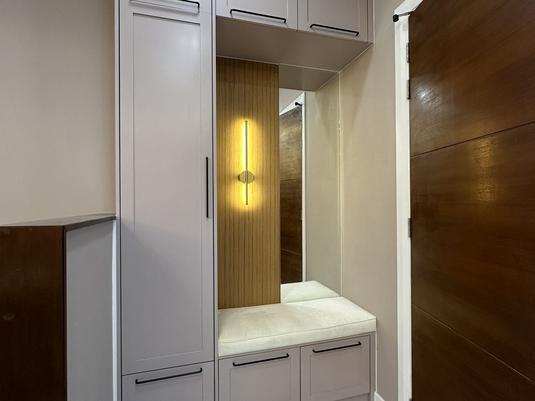 Foyer storage bench with a mirror and fluted timber panel under a linear sconce