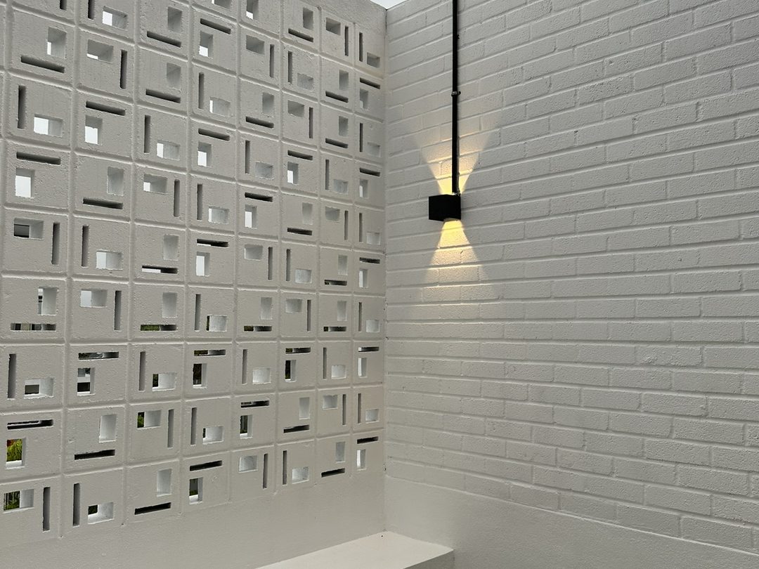 Courtyard with a white breeze-block screen wall, built as part of the home, Jardin Residence