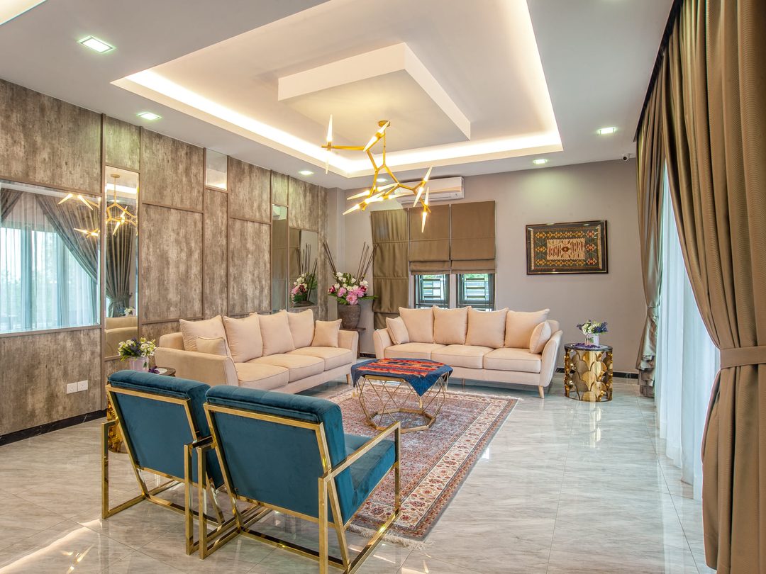 Living room interior design with brass-framed lounge chairs and layered lighting, Nilai Impian