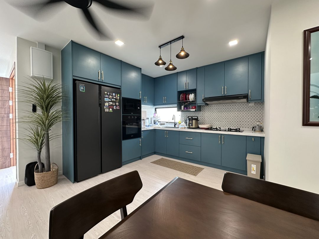 Teal kitchen with brass pendant lights and a dark integrated fridge