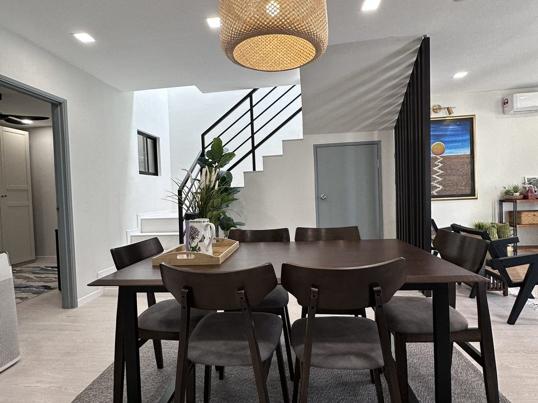 Dining table under a rattan pendant light beside the staircase