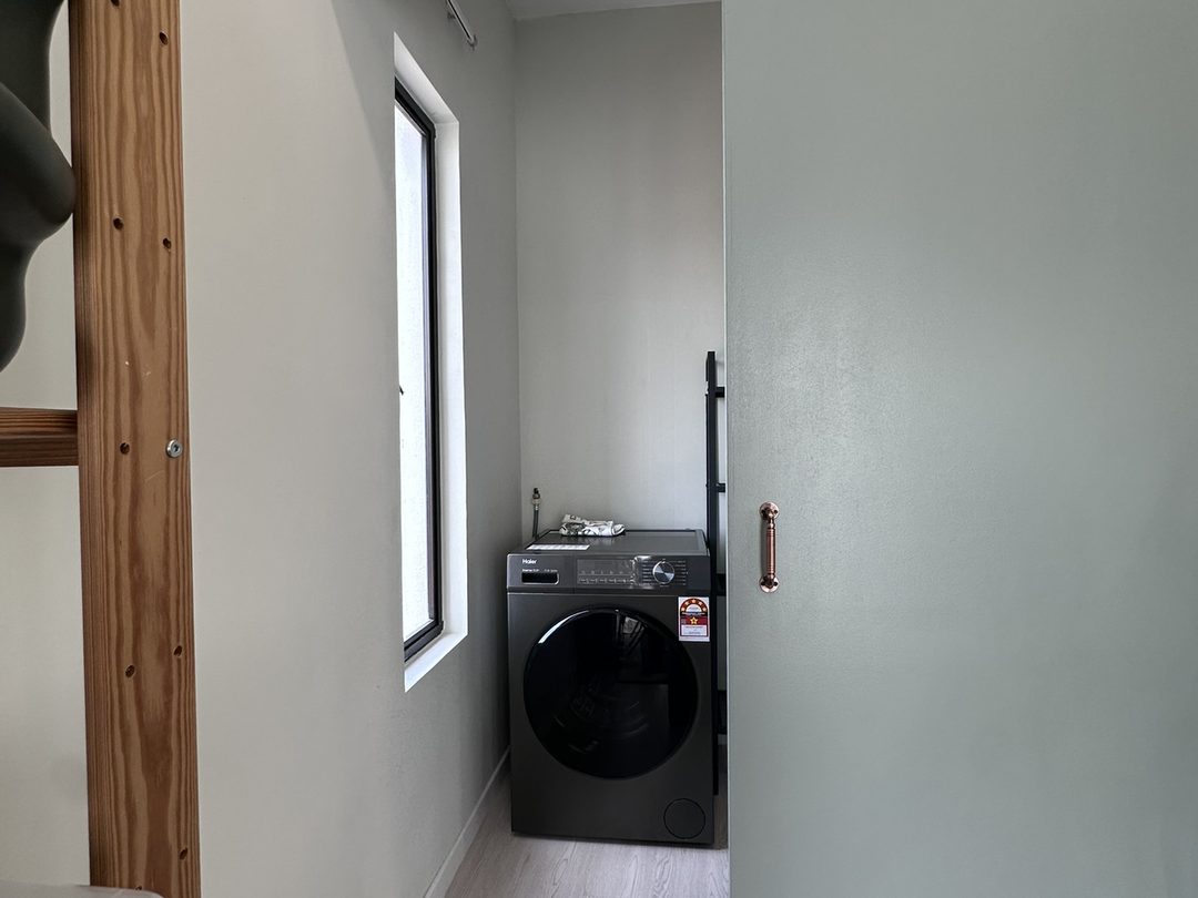 Laundry nook behind a pale green sliding barn door